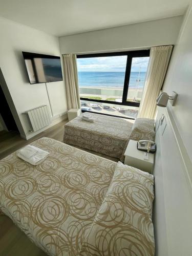 a bedroom with two beds and a view of the ocean at Costanera Hotel in Puerto Madryn