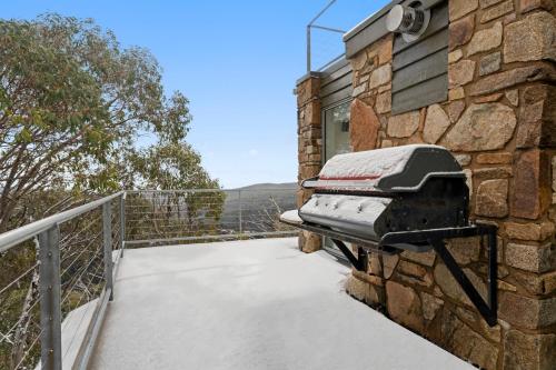 a balcony with snow on a stone wall at Candoux 2 AMS Mt Buller in Mount Buller