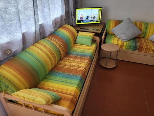 a bedroom with a couch with a rainbow blanket at Residenza Verde Mare Cugnana village in Cugnana Verde