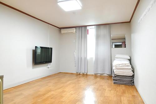 a room with white walls and a flat screen tv at Sorak Hostel in Sokcho