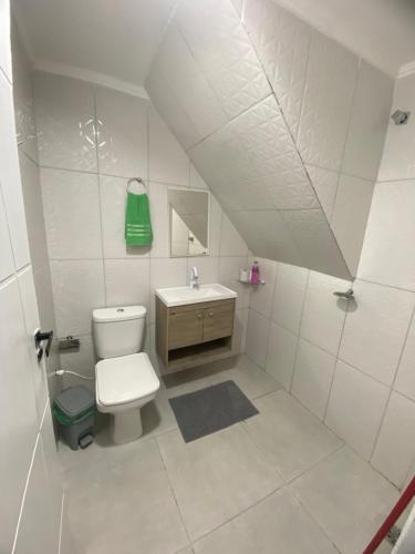 a white bathroom with a toilet and a sink at Suites mirante da Enseada in Guarujá