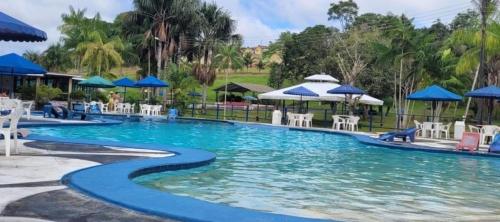 a pool at a resort with blue umbrellas and chairs at Chalé 01 Acqua Park - 06 km de Presidente Figueiredo-AM in Presidente Figueiredo