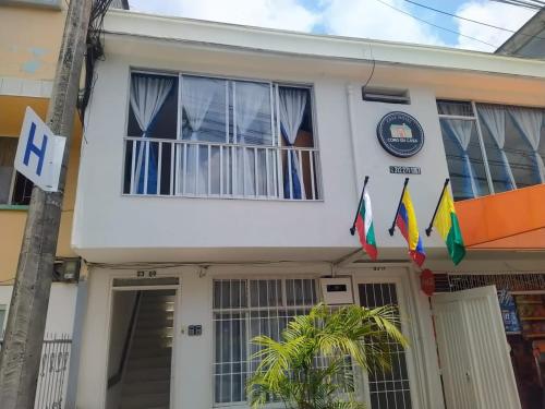 a white house with flags in front of it at Casa hotel cómo en casa in Manizales