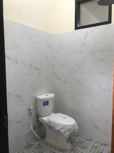a bathroom with a toilet with white marble walls at Lahar Villa Lombok in Masbagik