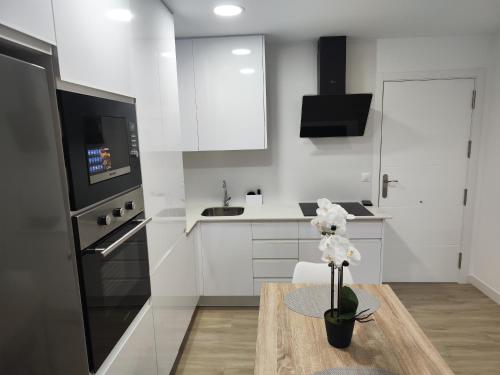a kitchen with white cabinets and a wooden table at Torregóndolas A1 in Torrenueva