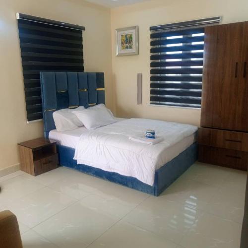 a bedroom with a bed with a blue headboard at DELCHIZZ Apartment in Mama