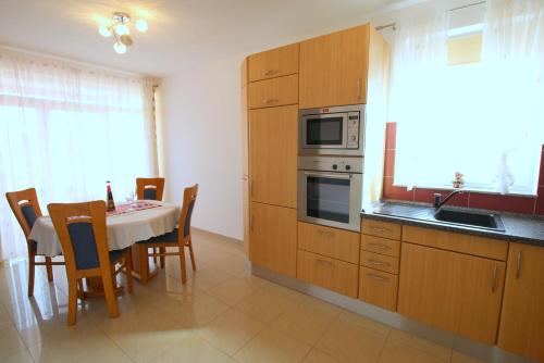 eine Küche mit einem Tisch mit Stühlen und einer Mikrowelle in der Unterkunft Apartment Luzia in Banjole