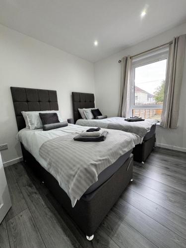 two beds in a bedroom with a large window at Modern and stylish 3 bedroom 2 bathroom west end house with Free WiFi and parking in Scotstoun West Station
