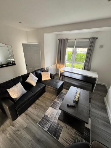 a living room with a black couch and a table at Modern and stylish 3 bedroom 2 bathroom west end house with Free WiFi and parking in Scotstoun West Station