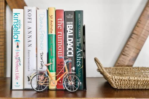 a group of books sitting on a shelf at Mollymook Memories - close to beach & golf course in Mollymook