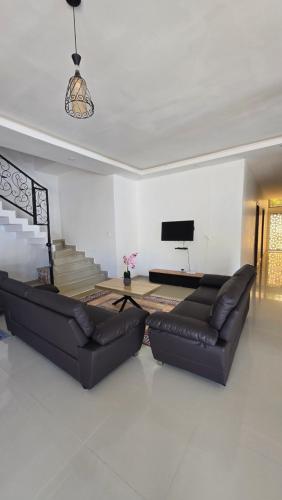 a living room with two leather couches and a television at Villa with pool, close to sea in Warang