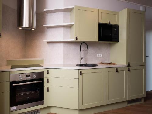 a kitchen with white cabinets and a sink at Cozy Bungalow by the Lake in Antoing