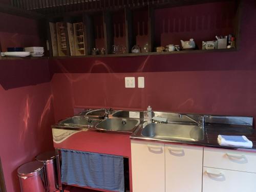 a kitchen with two sinks and a red wall at Higashiyama Komachi in Kanazawa