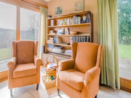 two orange chairs in a living room with a book shelf at Quiet valley view retreat in Roy