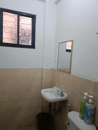 a bathroom with a sink and a toilet and a mirror at Chelsea's Haven - Entire House in Bacolod