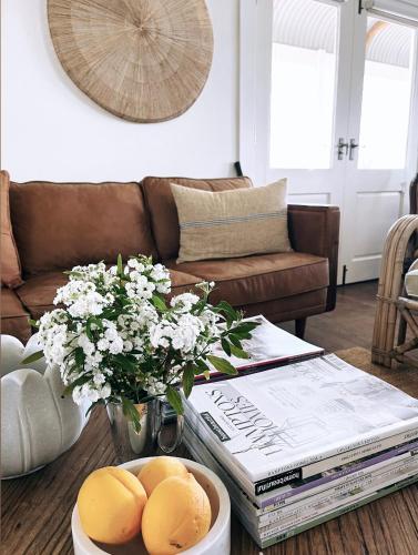 a living room with a coffee table with books and flowers at Gorgeous Country Cottage In Lovely Private Grounds in Scone