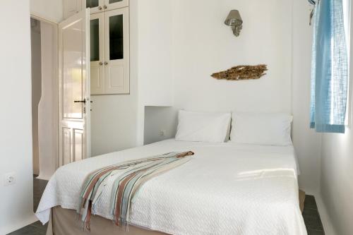 a bedroom with a white bed with a striped blanket on it at Skaris Guesthouse Tinos in Pánormos