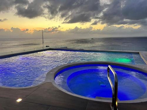 a large swimming pool with a view of the ocean at Modern studio in a waterfront building in Cozumel