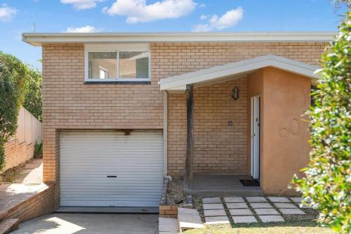 a brick house with a garage and a window at Ocean Overlook - Rennies Beach holiday haven in Ulladulla