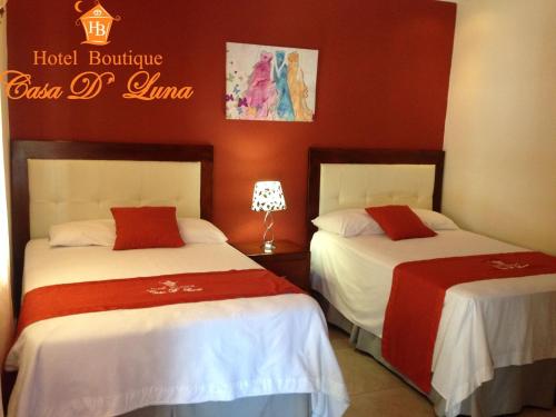 two beds in a hotel room with red walls at Hotel Boutique Casa D' Luna in Choluteca