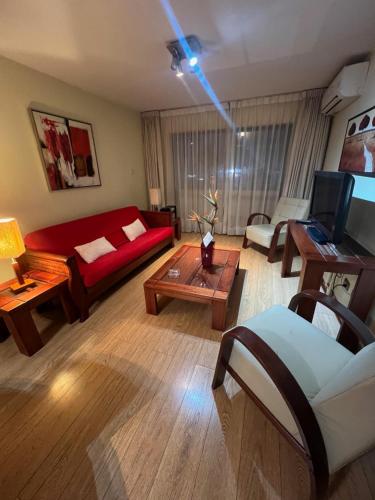 Una sala de estar con un sofá rojo y una mesa. en Departamento Coyancura, en Santiago