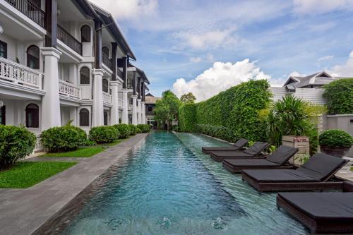 a pool in the middle of a building with chaise lounges at Siri Village Chiang Mai in Chiang Mai