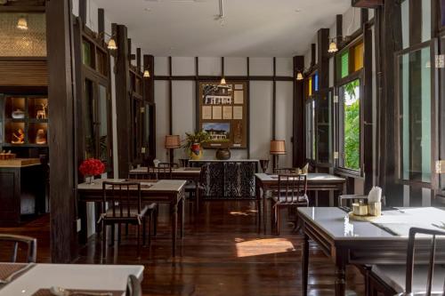 a restaurant with wooden tables and chairs and windows at Siri Village Chiang Mai in Chiang Mai