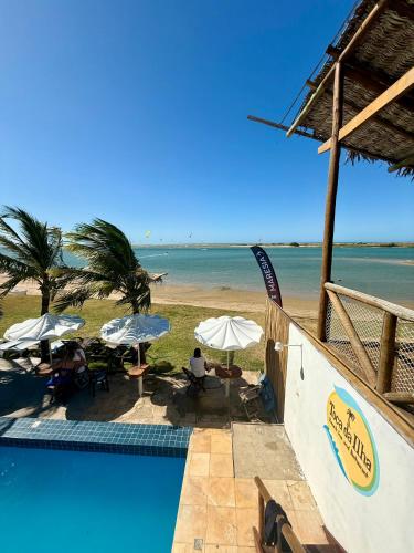 a swimming pool next to a beach with umbrellas at Toca da Ilha in Itarema