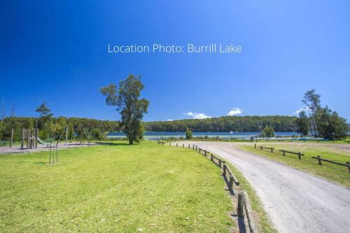 a dirt road in a field next to a lake at Stunning Views - beach cottage with ocean vistas in Burrill Lake