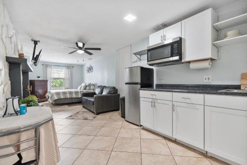 a kitchen with white cabinets and a living room at PRIVATE STUDIO near Busch Gardens & USF in Tampa