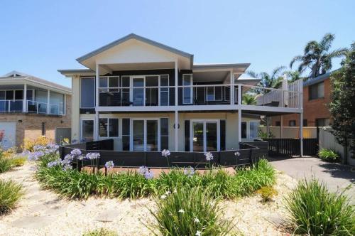 a house on the beach with flowers at Arcadia - large 4BR beach home & optional studio in Vincentia