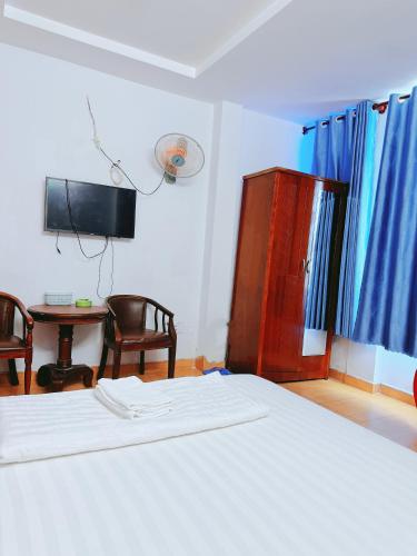 a bedroom with a bed and a tv and a table at Khách Sạn Bảo Long in Ho Chi Minh City