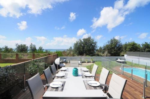 a patio with a table and chairs and a swimming pool at Bella Blu Beach House - direct beach access in Vincentia