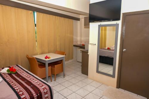 a room with a bed and a table and a mirror at Grand Melanesian Hotel in Nadi