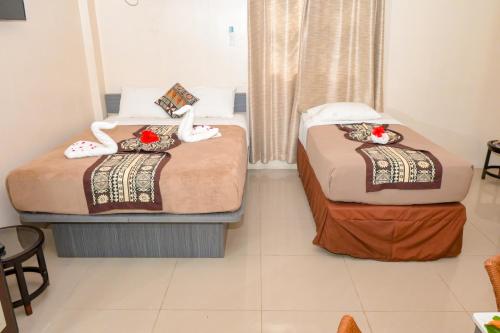two beds in a hotel room with flowers on them at Grand Melanesian Hotel in Nadi