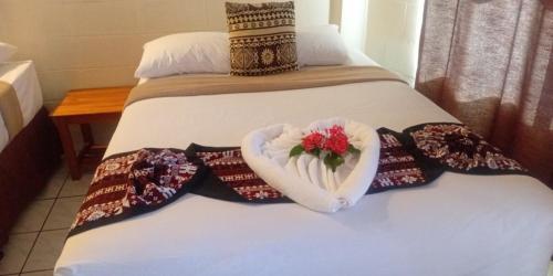 a bed with a heart shaped towel and a bouquet of flowers at Grand Melanesian Hotel in Nadi