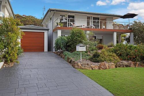 a house with a wooden garage and a walkway at Escape to Hyams Beach by Jervis Bay Rentals in Hyams Beach