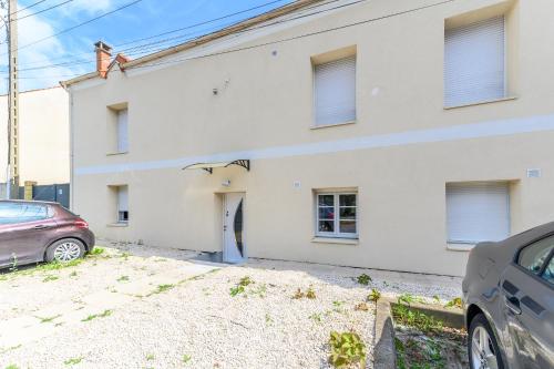 a white house with a car parked in front of it at Le cocon de l'impasse à Tremblay en France in Tremblay En France