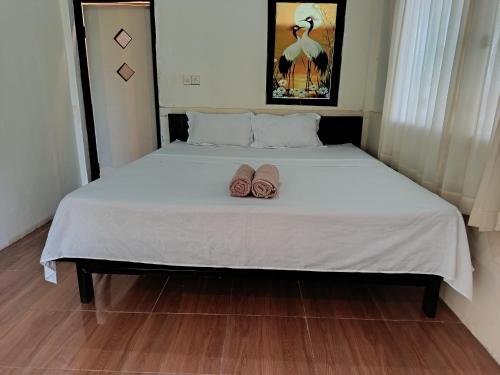 a bed with two pairs of slippers on it at The Daun Puntik HomeStay in Pawenang