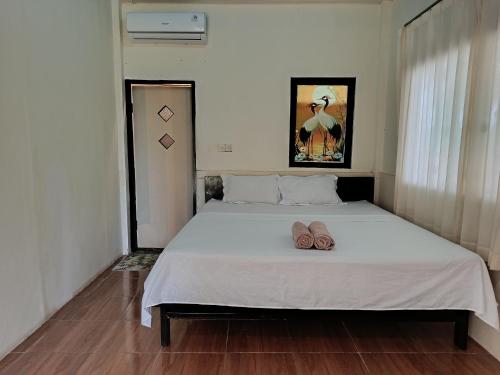 a bedroom with a bed with two slippers on it at The Daun Puntik HomeStay in Pawenang