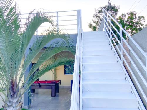 a staircase leading up to a house with a palm tree at A Casa Paradisíaca Total Luxuoso Piscina Super Hiper Mega Quente 50 graus Aquecimento Elétrico , Sinuca e 5 Quartos Com Ar Condicionado Com Roupa de Cama e Banho in Caldas Novas