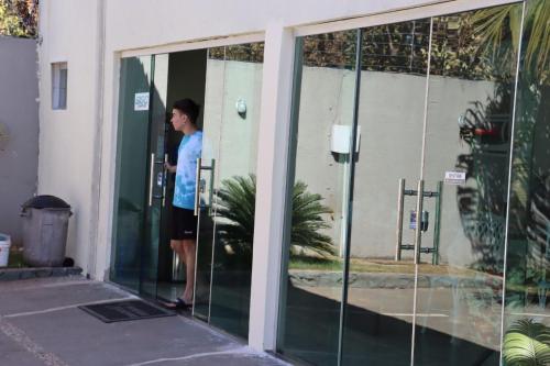 a person standing inside of a glass door at A Casa Paradisíaca Total Luxuoso Piscina Super Hiper Mega Quente 50 graus Aquecimento Elétrico , Sinuca e 5 Quartos Com Ar Condicionado Com Roupa de Cama e Banho in Caldas Novas