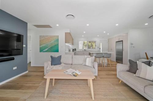 a living room with a couch and a table at Elements of Hyams - perfect Hyams Beach getaway in Hyams Beach