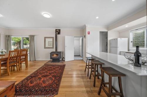 a kitchen with a long counter and chairs and a stove at Bowen View - pet-friendly home near Hyams Beach in Hyams Beach