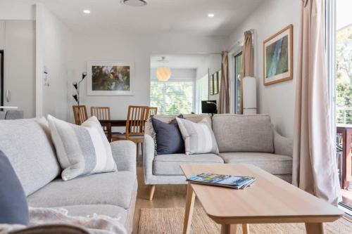 a living room with two couches and a table at Elements of Hyams - perfect Hyams Beach getaway in Hyams Beach