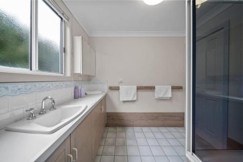 a white bathroom with a sink and a shower at Bowen View - pet-friendly home near Hyams Beach in Hyams Beach