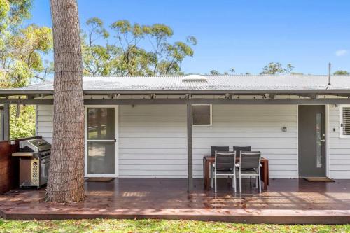 a house with a table and chairs on a porch at Elements of Hyams - perfect Hyams Beach getaway in Hyams Beach