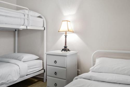 a lamp on a dresser in a bedroom with two beds at Footprints at Hyams Beach - 4BR home w. games room in Hyams Beach
