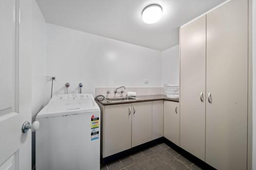 a white kitchen with a sink and a refrigerator at Footprints at Hyams Beach - 4BR home w. games room in Hyams Beach