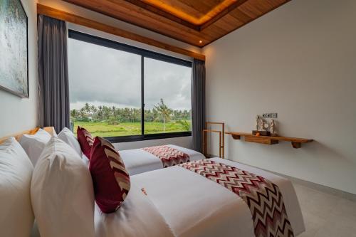 two beds in a room with a large window at Greha Natha Villa Ubud in Ubud